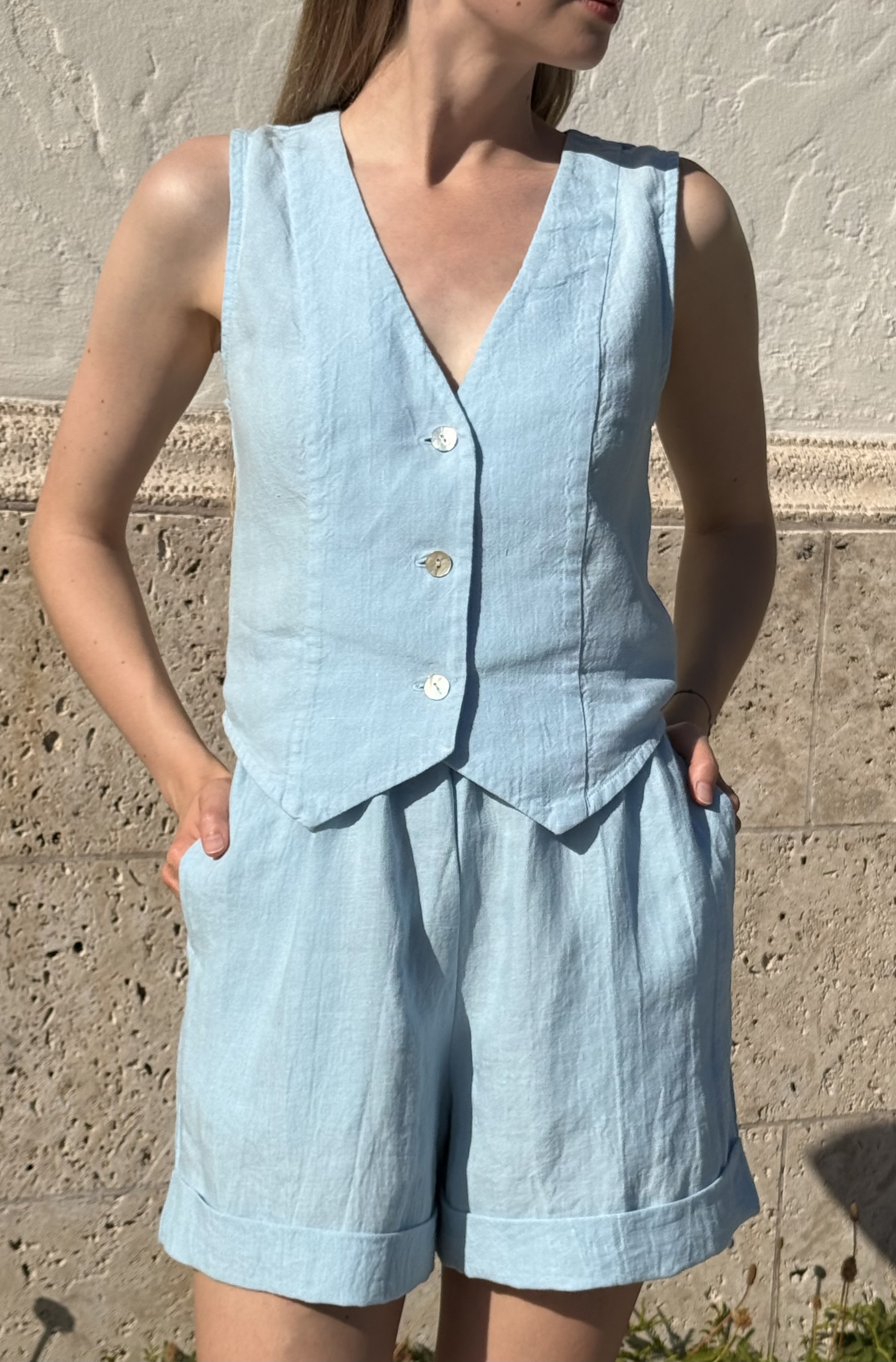 Vest worn with linen shorts against a stone wall